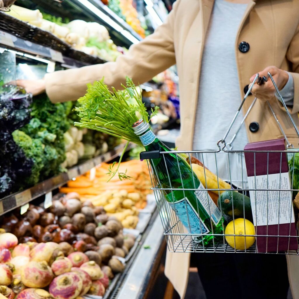 Woman selecting produce with a grocery basket